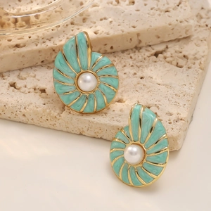 Detailed close-up of mint green conch stud earrings with pearls on a travertine stone