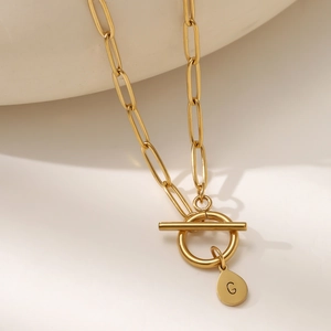 Macro view of gold paperclip chain necklace with OT toggle clasp and G letter pendant