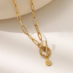 Detailed close-up of gold paperclip chain necklace with T-bar OT clasp and letter I pendant