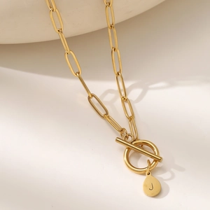 Detail of gold paperclip chain necklace with OT toggle clasp and letter J pendant