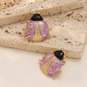 Dettaglio ravvicinato di orecchini a coccinella viola su base in pietra naturale