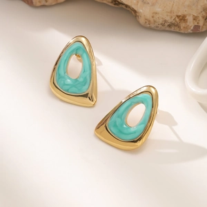 Detailopname van gouden geometrische oorbellen met turquoise emaille inlegwerk