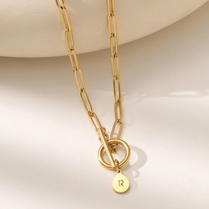 Macro shot of gold stainless steel paperclip necklace with letter R pendant and toggle clasp