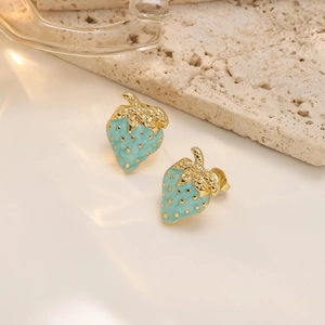 Detail view of light blue strawberry earrings with gold leaf accents on a stone background