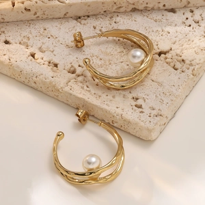 Detailed close-up of gold layered hoop earrings featuring irregular texture and white pearls