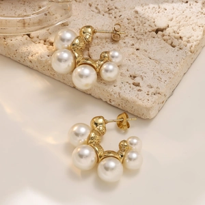 Close-up of vintage gold C-shaped earrings with pearls and hammered texture