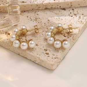 Detailed macro view of 18K gold-plated C-shaped earrings with hammered texture and pearls