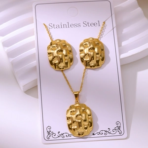 Detailed macro view of vintage gold-plated stainless steel jewelry set with embossed texture