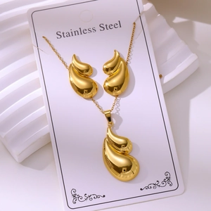 Detailed macro view of gold-plated teardrop necklace and earrings set in stainless steel
