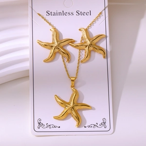 Detail view of gold starfish necklace and earring set on a stainless steel card