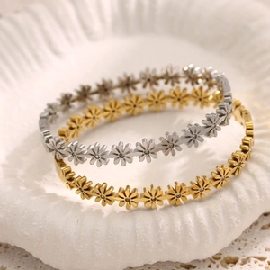 Elegant 18K gold and silver daisy bracelets with zircon stones on a shell tray