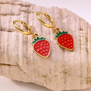 Chic gold hoop earrings featuring red strawberry charms on a natural stone surface