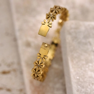 Macro detail of the gold daisy flower clasp and crystal centers on the linked bracelet