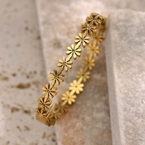 Elegant 18K gold-plated daisy bracelet with sparkling diamond centers on beige stone