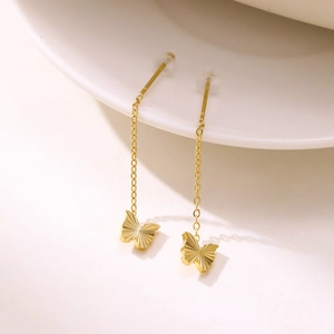 Elegant gold butterfly tassel drop earrings with long chain design on white ceramic base
