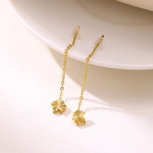 Golden long chain tassel earrings with maple leaf pendant on minimalist white background