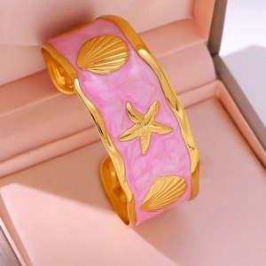 Roze emaille C-vormige armband met gouden zeester en schelpbedels op fluweel