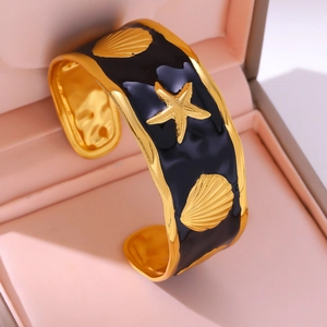Detailweergave van de zwarte emaille armband met gouden zeesterren en schelpenreliëfs