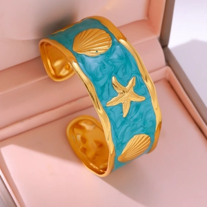 Detail van gouden zeesterren en schelpen op een turquoise geëmailleerde brede armband