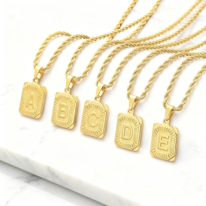 Detalle de colgantes de letras rectangulares chapados en oro con cadenas de cordón
