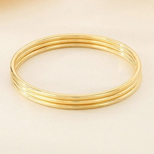 Detailed view of three polished 3mm gold stainless steel bangles with glossy finish