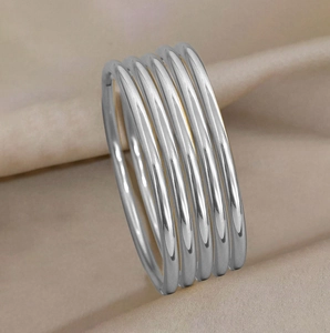 Macro detail of high-polished 3mm stainless steel stackable rings on beige silk fabric