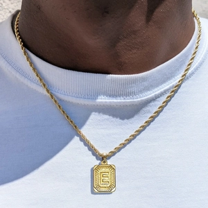 Detalle del collar de cadena torcida en oro de 18k con colgante cuadrado letra E en modelo