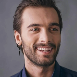 Close-up of black stainless steel huggie earring with spike pendant on a male model