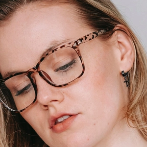 Close-up of black stainless steel cross hoop earring worn by a model in a lifestyle shot