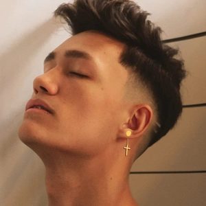 Close-up of a man wearing a polished gold stainless steel cross pendant stud earring