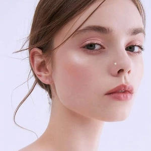 Close-up of a minimalist tiny silver nose stud with a micro-diamond on a female model