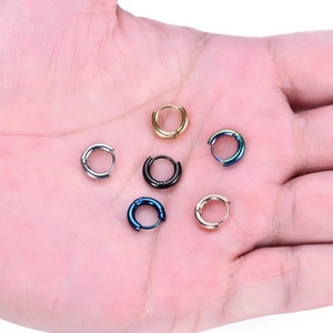 Set aus 6 bunten Edelstahl-Huggie-Ohrringen, zur Größenbestimmung in der Hand gehalten