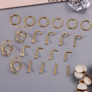 Detail of 21-piece gold nose ring set with zirconia accents on a grey textured background