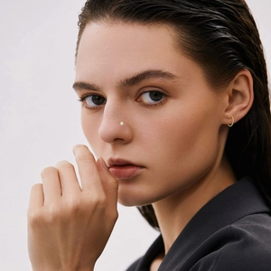 Close-up of a model wearing a minimalist gold nose stud set with a clear sparkling crystal