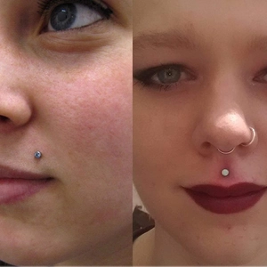 Detail of nose studs and labret piercings with blue and white opal stones set in steel