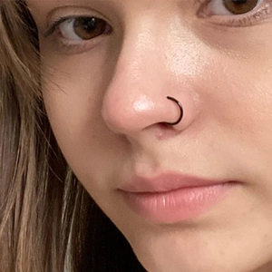 Minimalist black stainless steel nose ring hoop shown on model with matte finish
