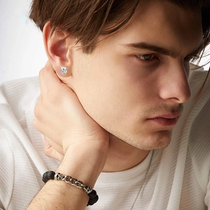 Detalle de set punk para hombre con pulsera de cuentas negras y pendiente de circonita