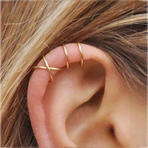 Detail of three gold ear cuffs featuring criss-cross and slim hoop designs on cartilage