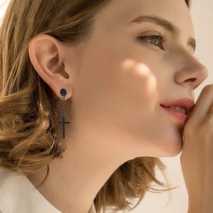 Close-up of model wearing black stainless steel cross earring with minimalist chain link