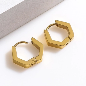 Nahaufnahme hexagonaler vergoldeter Edelstahl-Creolen auf minimalistischem weißem Hintergrund