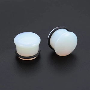 Macro detail of opal ear plugs with black O-rings on a dark textured background
