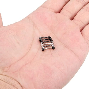 Detailed macro view of five assorted curved eyebrow rings held in a hand for scale