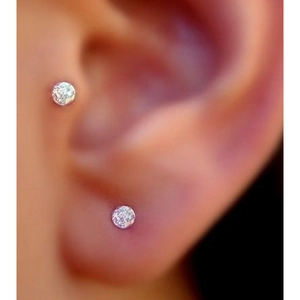 Close-up of minimalist clear crystal stud earring worn on lobe and tragus piercing