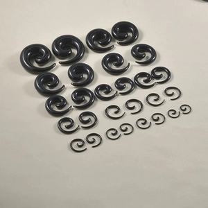 Set aus schwarzen Spiral-Dehnungsschnecken aus Acryl in verschiedenen Größen auf grauem Grund