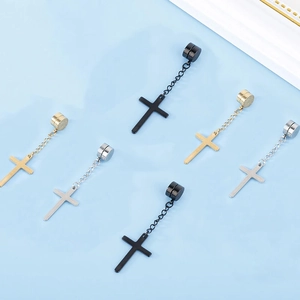 Flat lay of magnetic cross pendant earrings in black, gold, and silver stainless steel