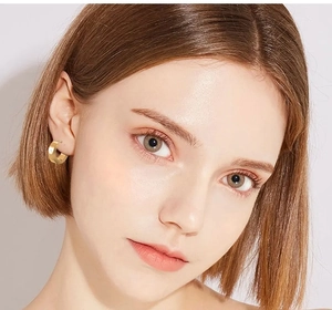 Close-up of classic wide gold-plated stainless steel hoop earrings worn on ear