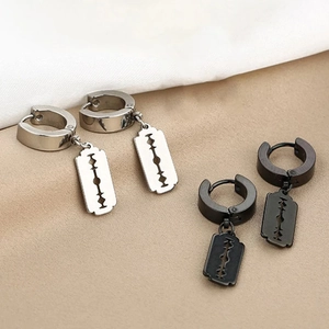 Detail of silver and black stainless steel huggie earrings with blade pendants