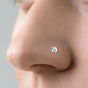 Macro shot of silver stainless steel nose stud with clear round diamond-cut crystal