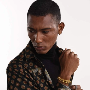Gros plan sur un clou d'oreille doré et un bracelet à chaînes sur un mannequin homme