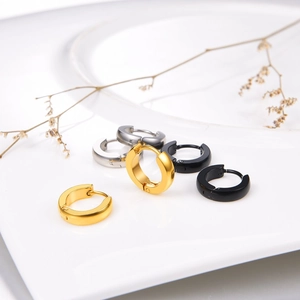 Trois paires de boucles d'oreilles en acier inoxydable or argent et noir sur une plaque